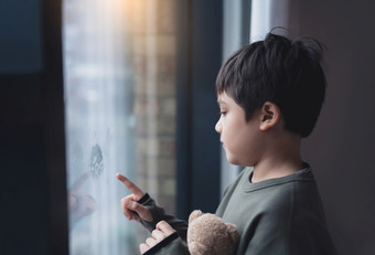 肖像学校男孩站下一个窗口和使用他的手指画写作窗口玻璃一边视图孩子手画玻璃蹒跚学步的男孩看他自我通过窗口