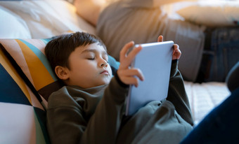 年轻的男孩下降<strong>睡眠</strong>而看<strong>卡通</strong>平板电脑试着孩子说谎床上玩游戏在线孩子睡觉而阅读电子书数字平板电脑学校男孩放松首页