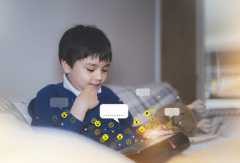 快乐孩子使用平板电脑会说话的在线与朋友与通知图标弹出孩子与微笑脸使用数字垫聊天玩游戏互联网课外的社会媒体网络