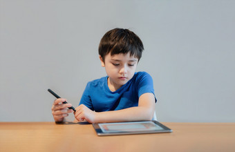 <strong>学校</strong>孩子学习在线类房间首页孩子使用平板电脑为家庭作业年轻的男孩研究在线视频调<strong>用电</strong>子学习在家教育教育概念