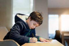 学校孩子使用黑色的笔画写作的信纸年轻的男孩做家庭作业孩子与笔写作笔记纸表在的教训可爱的学生做测试在家教育概念