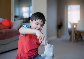 快乐年轻的男孩说谎地板上玩与<strong>狗玩具</strong>孩子与微笑脸玩独自一人首页周末积极的孩子放松首页的早....