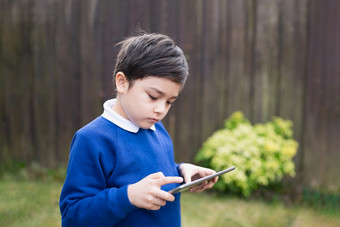 快乐孩子男孩持有平板电脑站外等待为学校公共汽车肖像孩子玩游戏在线阅读strory互联网学前教育男孩学习与现代技术