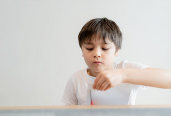 孩子使用剪刀切割白色纸小学生使艺术和工艺为他的家庭作业孩子学习如何使用的剪刀减少的纸孩子们学习和玩首页首页学校概念