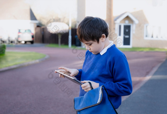 快乐孩子男孩持有平板电脑站外等待为学校公共汽车肖像孩子玩游戏在线阅读故事互联网孩子们学习与现代技术