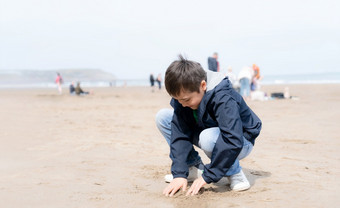 肖像快乐年轻的男孩玩和挖掘沙子的海滩阳光明媚的一天夏天孩子<strong>有有</strong>趣的与建筑沙子城堡热带海滩与模糊的背景人走的海