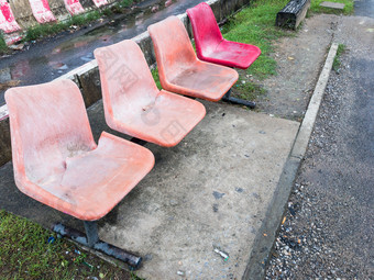 老塑料椅子的金属行为乘客的铁路站平台附近的城市区域