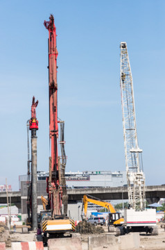 大钻井机和白色起重机与模糊焦点工作为建的大运输中心附近的城市区域