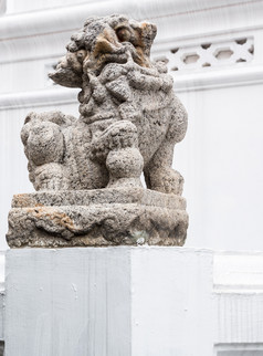 石头狮子雕像的传统的中国人风格哪一个位于附近的寺庙墙为装饰的泰国寺庙