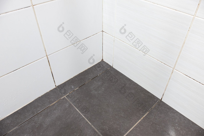的地板上瓷砖与宽松的灌浆和的脏墙瓷砖附近的角落里的浴室前面视图与的复制空间