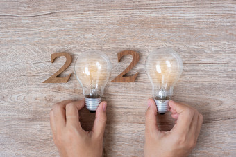 快乐新一年与商人持有灯泡与崩溃了纸和木数量表格新开始的想法有创意的创新决议解决方案策略目标和任务概念