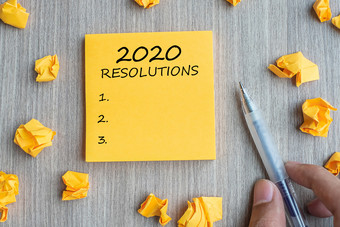 决议词黄色的请注意与商人持有笔和崩溃了纸木表格背景新一年开始策略和目标概念