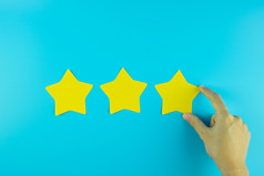 客户持有三个明星黄色的纸请注意蓝色的背景客户评论反馈评级排名和服务概念