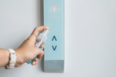 女人手喷涂酒精洗手液瓶的按钮控制电梯对小说冠状病毒电晕病毒疾病新冠病毒公共室内防腐剂卫生和医疗保健概念