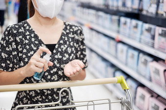 亚洲女人清洁手酒精喷雾在购物超市杂货店保护冠状病毒变形卫生新正常的和生活后新冠病毒流感大流行
