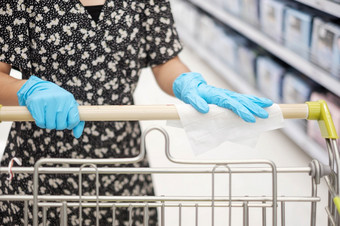 亚洲女人穿腈手套和清洁表面购物车湿擦超市杂货店保护冠状病毒变形卫生新正常的和生活后新冠病毒流感大流行