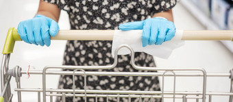 亚洲女人穿腈手套和清洁表面购物车湿擦超市杂货店保护冠状病毒变形卫生新正常的和生活后新冠病毒流感大流行