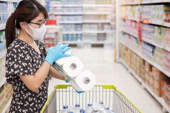亚洲女人穿保护面具和持有厕所。。。纸在购物超市杂货店保护冠状病毒变形卫生新正常的和生活后新冠病毒流感大流行