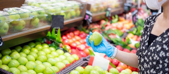 女人穿腈手套和持有绿色苹果水果超市杂货店保护冠状病毒变形卫生新正常的和生活后新冠病毒流感大流行