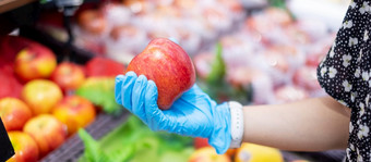 女人穿腈手套和持有红色的苹果水果超市杂货店保护冠状病毒变形卫生新正常的和生活后新冠病毒流感大流行