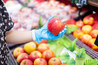 女人穿腈手套和持有红色的苹果<strong>水果超市</strong>杂货店保护冠状病毒变形卫生新正常的和生活后新冠病毒流感大流行