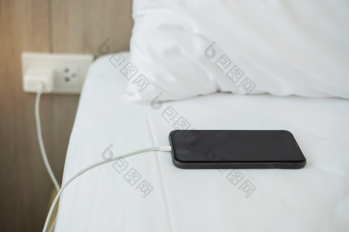 移动聪明的电话充电电池床上的卧室首页技术多个分享和生活方式概念