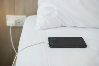 移动聪明的电话充电电池床上的卧室首页技术多个分享和生活方式概念