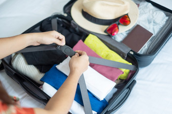 年轻的成人女包装行李为夏天假期女人旅游检查列表旅行配件手提箱的床上时间旅行放松旅程旅行和周末概念