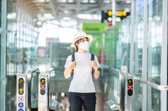 年轻的成人女穿脸面具机场终端保护冠状病毒疾病感染亚洲女人旅行者走自动扶梯飞机场新正常的和旅行下新冠病毒概念