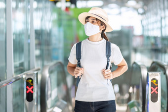 年轻的成人女穿脸面具机场终端保护冠状病毒疾病感染亚洲女人旅行者走自动扶梯飞机场新正常的和旅行下新冠病毒概念