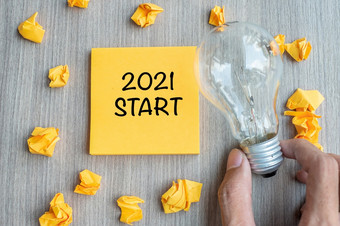 开始单词黄色的请注意和崩溃了纸与商人持有灯泡木表格背景新一年新的想法有创意的创新想象力决议和目标概念