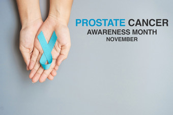 11月前列腺癌癌症意识月男人。持有光蓝色的丝带为支持人生活和疾病医疗保健国际但父亲世界癌症一天和世界糖尿病一天概念