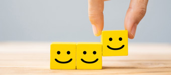 手持有微笑脸象征黄色的木多维数据集块情感服务评级排名客户审查满意度和反馈概念