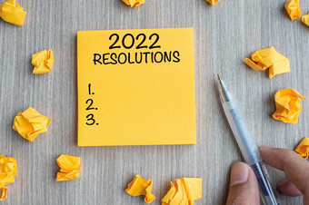 决议词黄色的请注意与商人持有笔和崩溃了纸木表格背景新一年开始策略和目标概念