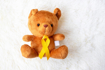 黄色的丝带与熊娃娃白色背景为支持孩子生活和<strong>疾病</strong>9月童年癌症意识月和<strong>世界</strong>癌症一天概念
