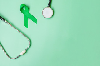 绿色丝带与听诊器绿色颜色背景为支持人生活和疾病<strong>肝胆</strong>囊甚至管癌症和器官捐赠意识月概念