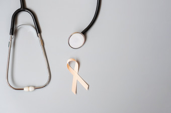 9<strong>月子</strong>宫癌症意识月桃子丝带与听诊器为支持人生活和疾病医疗保健和世界癌症一天概念