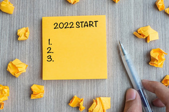 开始词黄色的请注意与商人持有笔和崩溃了纸木表格背景新一年决议策略和目标概念