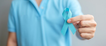 11月前列腺癌癌症意识月男人。蓝色的衬衫与手持有蓝色的丝带为支持人生活和疾病医疗保健国际但父亲和世界癌症一天概念