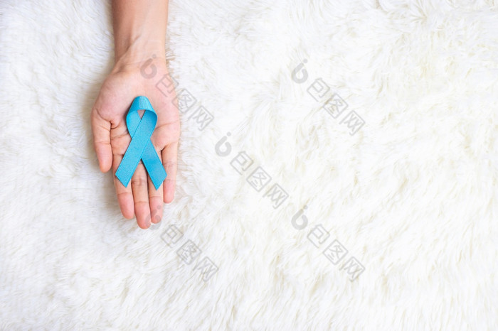 11月前列腺癌癌症意识月男人。持有光蓝色的丝带为支持人生活和疾病医疗保健国际但父亲世界癌症一天和世界糖尿病一天概念