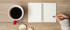 女人手写作笔记本与黑色的咖啡杯和圣诞节饼干表格圣诞节快乐新一年目标决议列表策略和计划概念
