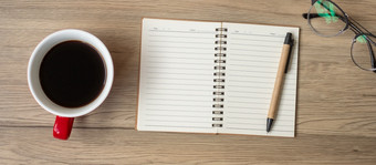 空白笔记本黑色的咖啡杯和笔木表格前视图和复制空间快乐新一年目标决议列表策略和计划概念