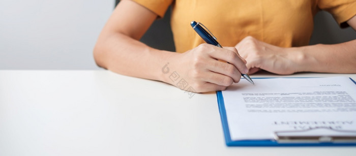女人签署合同文档后阅读手持有笔和批准业务