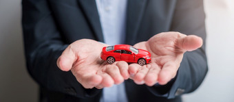 商人手持有红色的车玩具与车辆无钥匙笔<strong>和合</strong>同文档买和出售保险租赁<strong>和合</strong>同协议概念