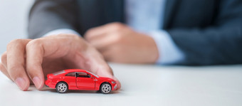 商人手持有红色的车玩具车保险保修租赁金融新和修复概念