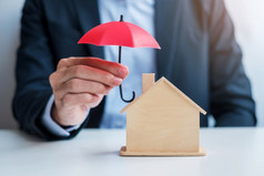 商人手持有红色的伞封面木首页模型真正的房地产保险和财产概念