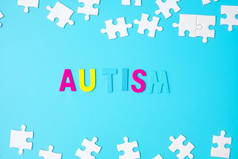 自闭症文本与白色谜题拼图块蓝色的背景概念健康自闭症光谱障碍和世界自闭症意识一天