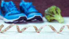 健康的概念饮食和健身体育运动鞋子西兰花白色木背景