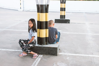 亚洲女孩和男孩等待为他们的父母的购物中心停车很多