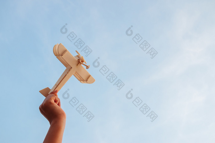 快乐孩子们玩木玩具飞机的日落天空背景